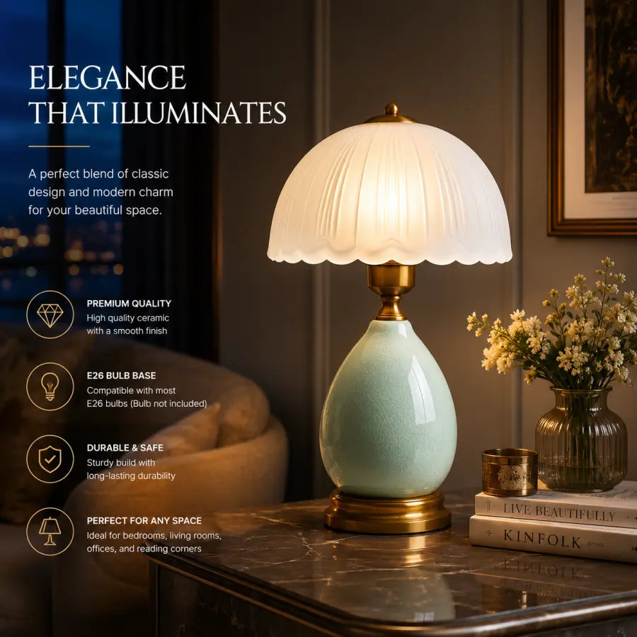 A classic-style table lamp with a scalloped white glass shade, a glossy pale green ceramic base, and a brass-toned collar and base, shown lit on a dark marble tabletop in a cozy interior setting with books and a vase of flowers. Text on the left highlights product features.